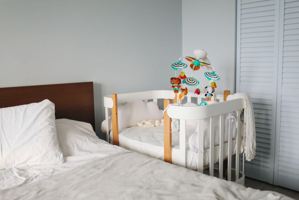 Baby cot beside a bed in a bedroom, illustrative image