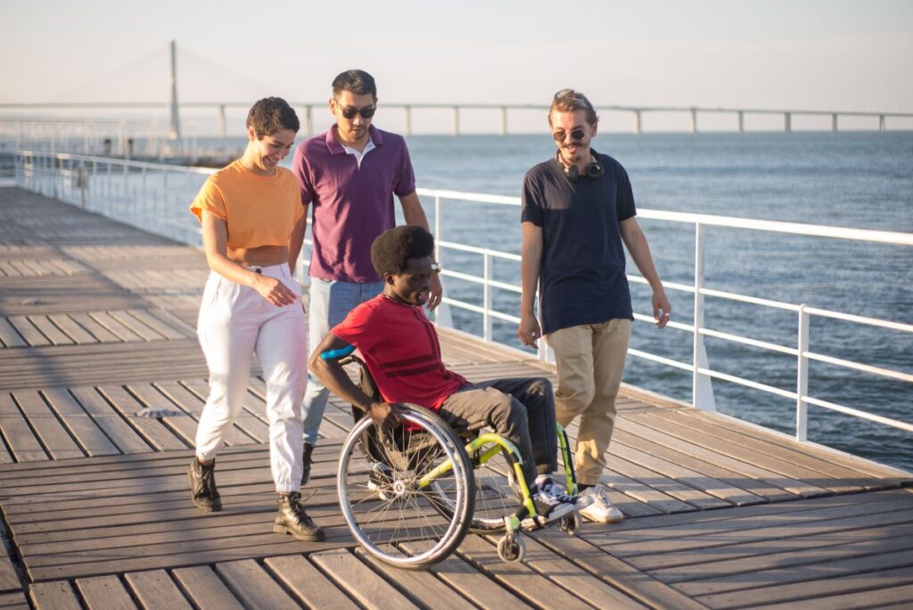 Wheelchair user and friends on a boardwalk, illustrative image